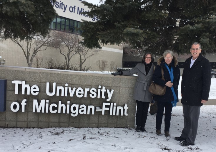 Three teachers standing in front of a sign