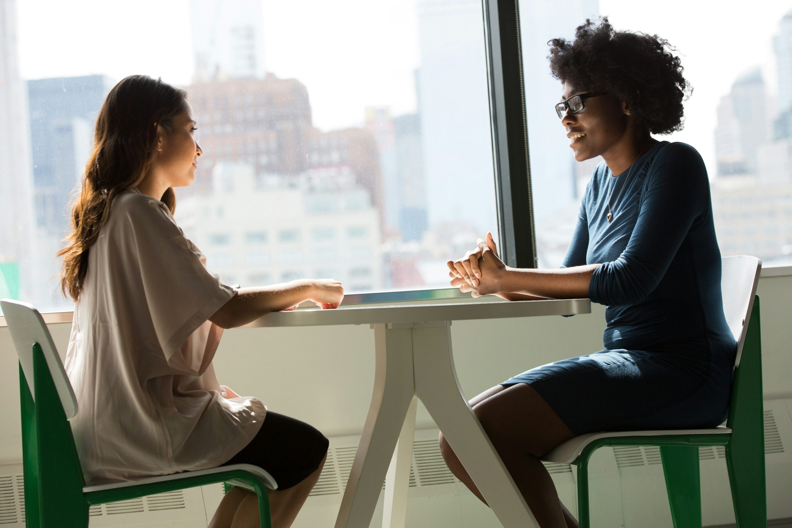 Two people sitting at a desk having a conversation.