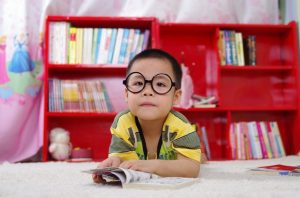 Student wearing glasses and reading a book