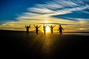 People jumping on the beach while looking into the sunset