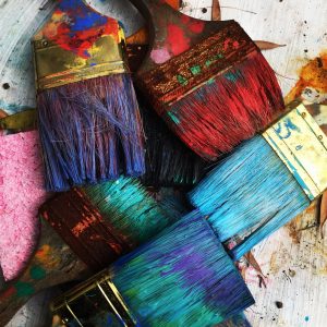 Paint brushes covered in colorful paint