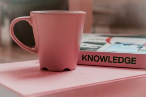 A coffee cup and a book that says "Knowledge"