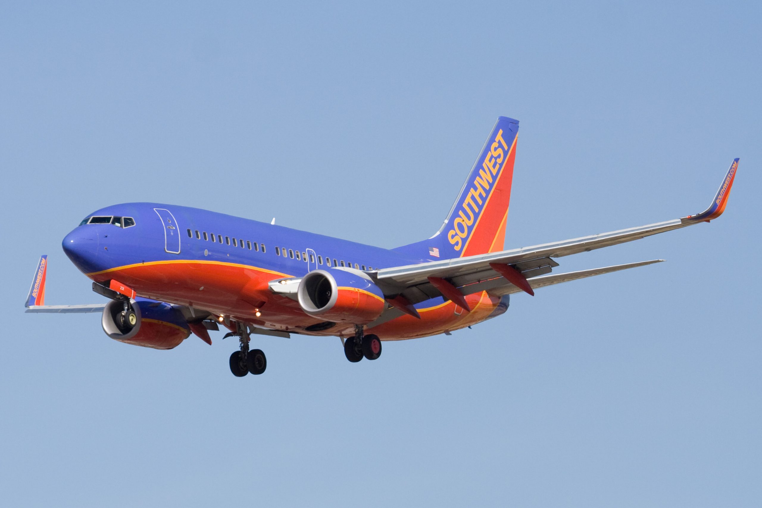 A Southwest Airlines airplane, blue and red coloured, flying against a clear blue sky.