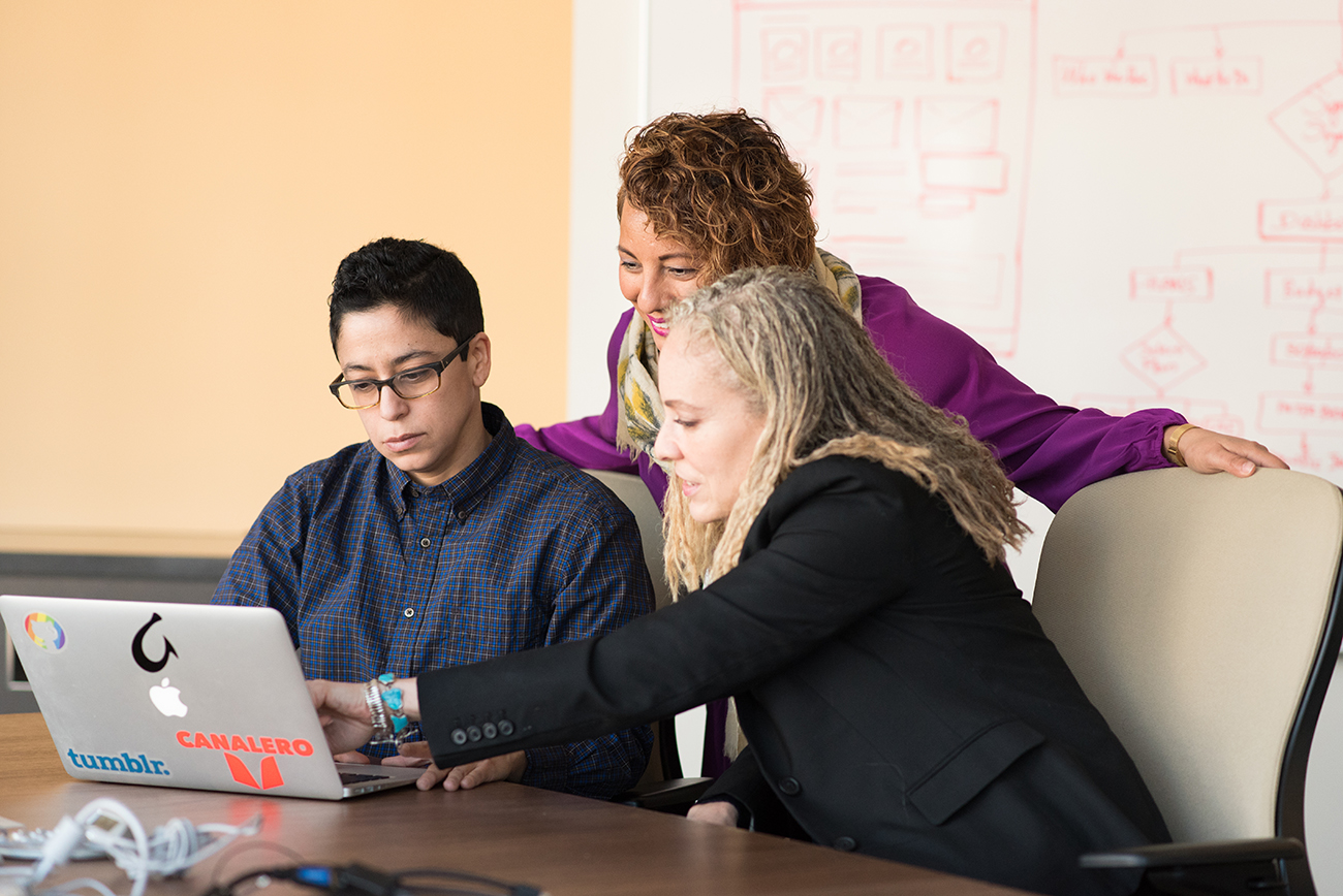 Diverse group of people working together on a laptop.