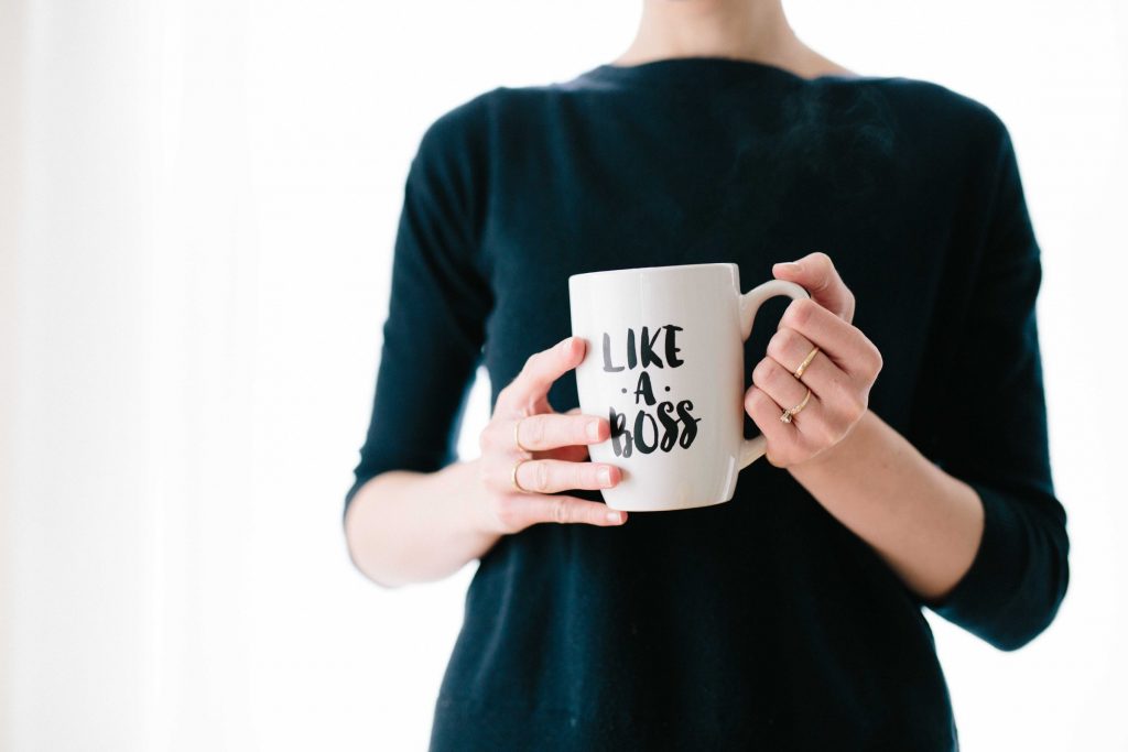 Woman holds a coffee mug that says "like a boss"