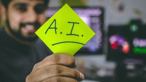 A an holding up a post it note that says, "AI"