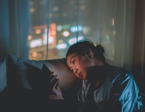 Woman looking at smartphone in dark setting.