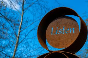 A metal sign that says, "Listen."